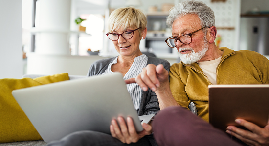 Couple sitting on the couch looking at tablets